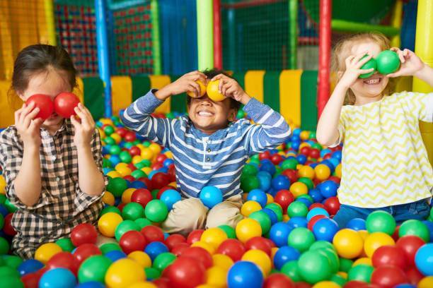 parkcover - Portrait of three funny little kids playing in ball pit and enjoying time in childrens entertainment and play area, copy space